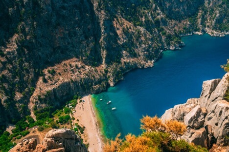 Kabak Koyu Fethiye'nin saklı cennetlerinden biri olan Kabak Koyu, doğal güzelliğini korumayı başarmış, modern dünyadan uzak huzur arayanların vazgeçilmez adreslerinden biridir. Yüksek tepelerle çevrili bu koy, el değmemiş doğası ve kristal berraklığındaki deniziyle büyüleyici bir atmosfer sunuyor. Çam ormanlarıyla kaplı yamaçlardan denize doğru inen patikalar, doğa yürüyüşü tutkunları için ideal rotalar oluşturuyor. Kabak Koyu'na hakim tepelerde konumlanan villalardan muhteşem deniz manzarasını seyredebilirsiniz. Özellikle gün doğumu ve gün batımı saatlerinde eşsiz fotoğraf kareleri yakalayabilirsiniz. Koyun etrafındaki zengin flora ve fauna, doğa fotoğrafçılığı için mükemmel fırsatlar sunuyor. Plajın kumsal kısmı oldukça geniş olup, denizi sığdan derine doğru kademeli bir şekilde ilerliyor. Bu özelliği sayesinde aileler için güvenli bir yüzme alanı oluşturuyor. Kabak Koyu'nun en dikkat çekici özelliklerinden biri de geceleri gökyüzünün berraklığı ve yıldızların parlaklığıdır. Kalabalık turizm merkezlerinden uzak, sakin bir tatil arayanlar için ideal bir destinasyondur. Gemile Koyu Tarihi kalıntıları ve turkuaz renkli deniziyle ünlü Gemile Koyu, antik dönemden günümüze uzanan zengin bir geçmişe sahiptir. Bizans döneminden kalma kilise kalıntıları ve su sarnıçlarıyla adeta açık hava müzesi niteliğindedir. Koyun etrafını çevreleyen çam ormanları ve kristal berraklığındaki denizi, ziyaretçilerine benzersiz bir doğa deneyimi sunuyor. Deniz dibindeki antik kalıntılar, özellikle snorkel ve dalış meraklıları için keşfedilmeyi bekleyen hazineler barındırıyor. Koyun sakin ve durgun denizi, yüzme tutkunları için ideal koşullar sağlıyor. Gemile Koyu'na yakın konumlanan villalardan muhteşem gün batımı manzarasını izleyebilirsiniz. Özellikle akşamüstü saatlerinde, güneşin batışıyla birlikte denizin ve gökyüzünün aldığı renk değişimleri büyüleyici bir görsel şölen sunuyor. Koyun çevresindeki yürüyüş parkurları, doğa yürüyüşü severler için alternatif rotalar oluşturuyor. Tekne turlarının popüler duraklarından biri olan Gemile Koyu, tarih ve doğanın muhteşem uyumunu gözler önüne seriyor. Sessiz ve sakin atmosferi, günlük hayatın stresinden uzaklaşmak isteyenler için ideal bir kaçış noktası oluşturuyor. Cennet Koyu Fethiye'nin en etkileyici noktalarından biri olan Cennet Koyu, ismini tam anlamıyla hak eden doğal güzelliklere sahiptir. Çam ağaçlarıyla kaplı tepelerin arasında gizlenmiş bu muhteşem koy, berrak suları ve el değmemiş doğasıyla ziyaretçilerini büyülüyor. Koyun kendine has mikroklima özelliği, yaz aylarında bile ferah bir ortam sunuyor. Denizi oldukça berrak ve dingin olan koy, özellikle yüzme ve şnorkel tutkunları için ideal koşullar sağlıyor. Cennet Koyu'na bakan yamaçlarda konumlanan villalardan panoramik deniz manzarasını seyredebilirsiniz. Koyun etrafındaki kayalık alanlar, deniz canlılarını gözlemlemek için mükemmel noktalar oluşturuyor. Plajın kumsal kısmı küçük olmasına rağmen, suyunun berraklığı ve derinliğinin kademeli artışı, güvenli bir yüzme alanı sunuyor. Tekne turlarının vazgeçilmez duraklarından biri olan Cennet Koyu, özellikle öğle saatlerinde verilen yüzme molalarında popüler bir nokta haline geliyor. Doğal yapısının bozulmamış olması ve erişimin kısıtlı olması, koyun bakir güzelliğini korumasını sağlıyor. Gün batımında koyun aldığı renk, fotoğraf tutkunları için eşsiz kareler yakalama fırsatı sunuyor. Günlük Koyu Günlük Koyu, Fethiye'nin gizli kalmış cennetlerinden biri olarak, doğal güzelliği ve sakin atmosferiyle öne çıkıyor. İsmini çevresindeki günlük ağaçlarından alan koy, antik dönemlerden beri şifa kaynağı olarak bilinen bu değerli ağaçların kokusunu tüm bölgeye yayıyor. Denizi turkuaz renkli ve son derece berrak olan koy, özellikle sakin ve huzurlu bir tatil arayanların tercih ettiği bir destinasyon. Günlük ağaçlarının gölgesinde serinleyebileceğiniz plajı, doğal bir klima etkisi yaratıyor. Koyun çevresindeki kayalık alanlar, deniz canlılarını gözlemlemek için ideal noktalar oluşturuyor. Özellikle sabah saatlerinde denizin durgunluğu, yüzme tutkunları için mükemmel koşullar sağlıyor. Koya hakim tepelerde konumlanan villalardan eşsiz deniz manzarasını izleyebilirsiniz. Bölgenin doğal yapısı korunduğu için, modern yapılaşmadan uzak, authentik bir tatil deneyimi sunuyor. Tekne turlarının uğrak noktalarından biri olan Günlük Koyu, özellikle günbatımı saatlerinde büyüleyici bir atmosfere bürünüyor. Koyun çevresindeki patika yollar, doğa yürüyüşü sevenler için keşfedilmeyi bekleyen rotalar sunuyor. 